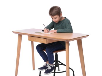 Boy with incorrect posture and notebook at wooden desk on white background