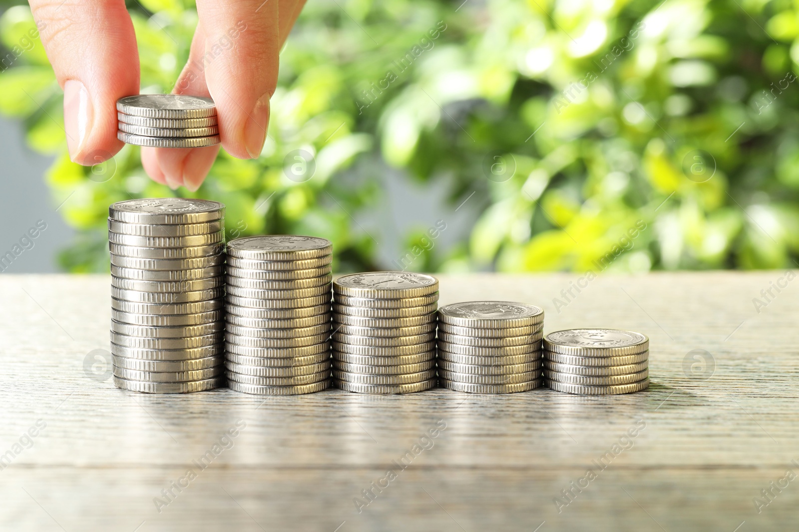 Photo of Salary concept. Woman putting coins on stack at grey table, closeup