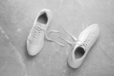 Photo of Pair of stylish sneakers on grey marble background, top view