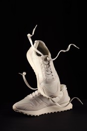 Photo of Pair of stylish sneakers in air against black background