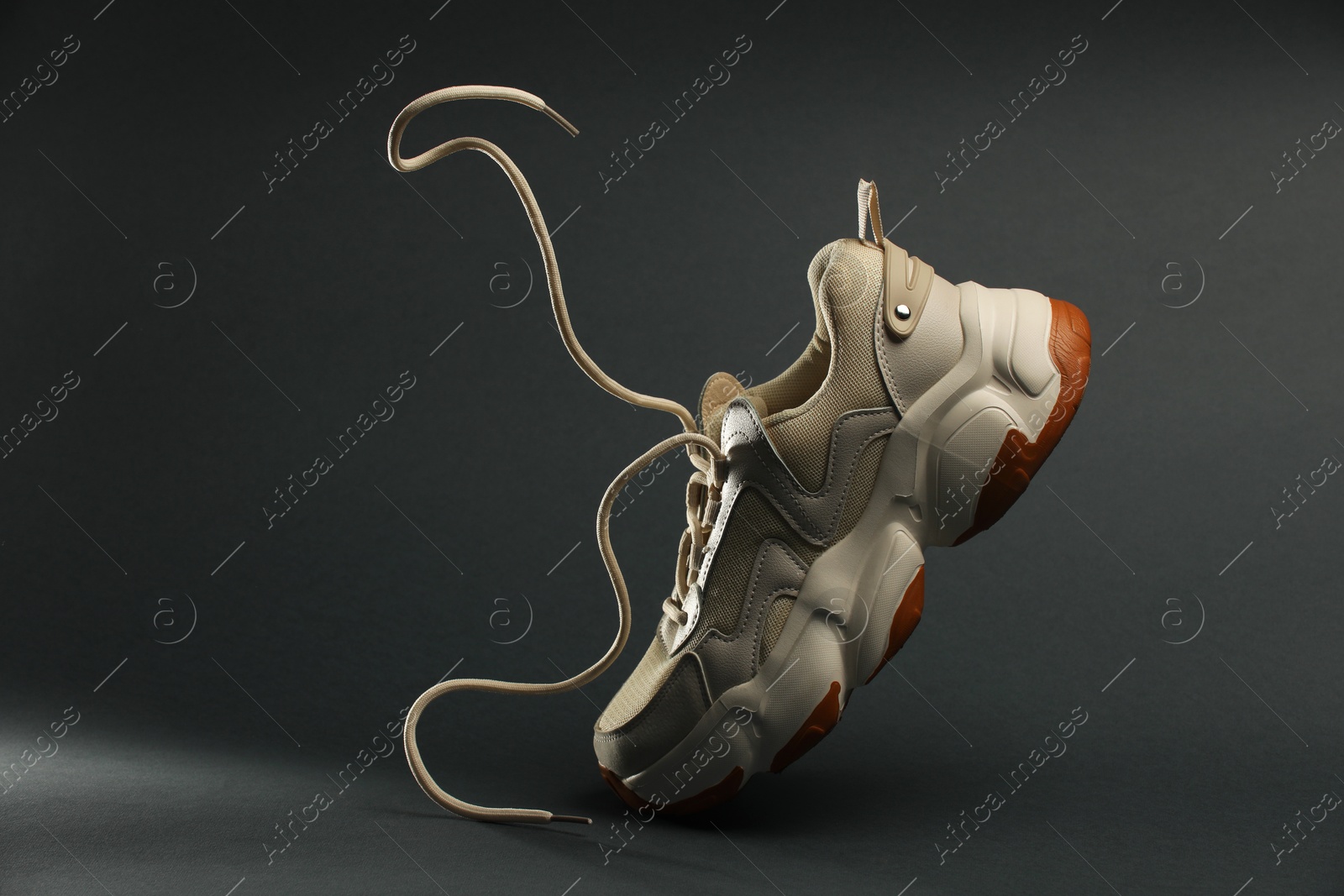 Photo of Stylish sneaker in air against grey background, space for text