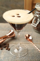 Photo of Delicious espresso martini with coffee beans in glass on wooden table