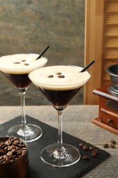 Photo of Glasses of delicious espresso martini with coffee beans on wooden table