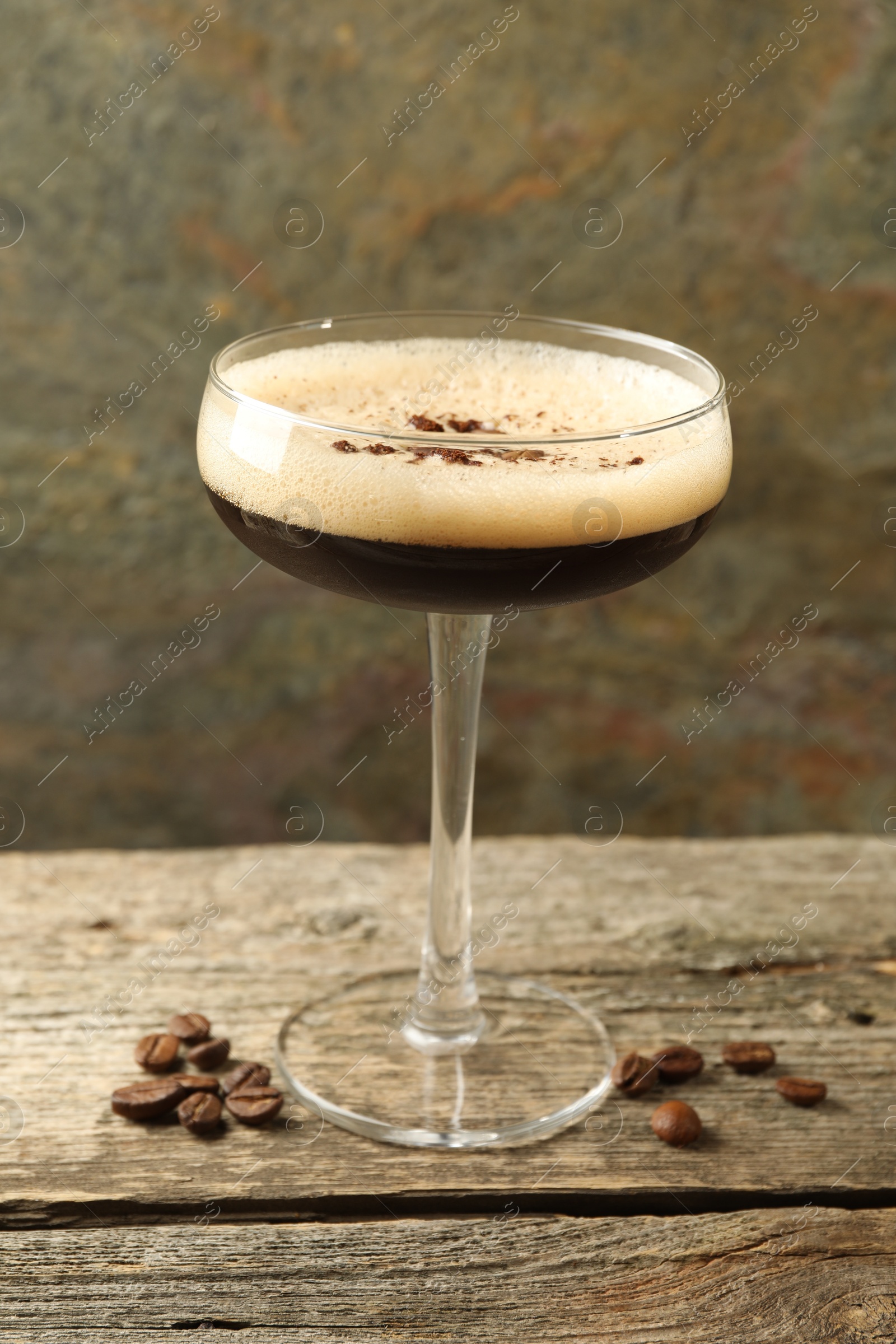 Photo of Delicious espresso martini with coffee beans in glass on wooden table