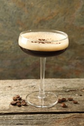 Delicious espresso martini with coffee beans in glass on wooden table