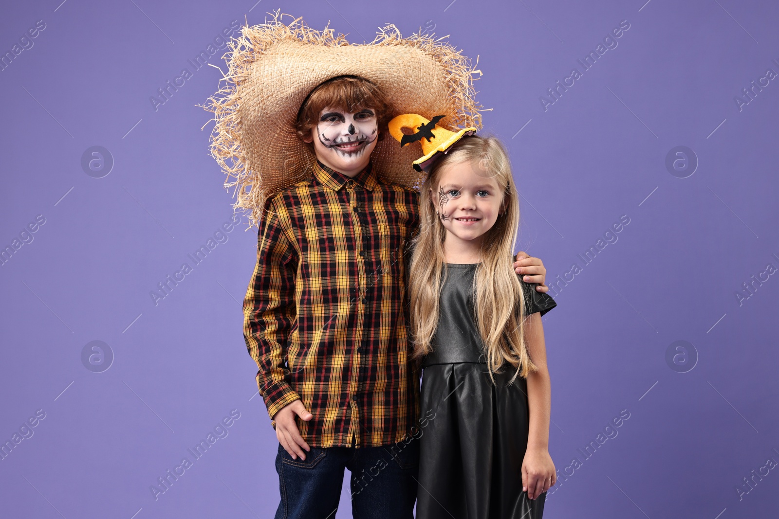 Photo of Cute children wearing costumes on violet background. Halloween celebration