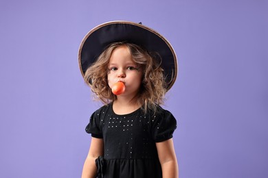 Photo of Funny girl with air balloon dressed like witch on violet background. Halloween celebration