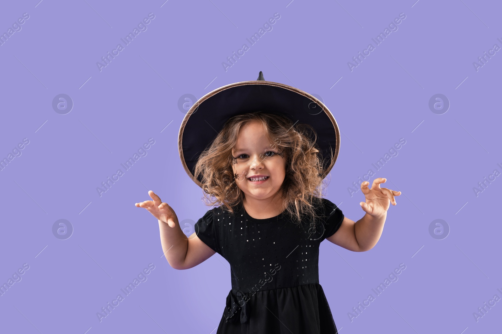 Photo of Funny girl dressed like witch for Halloween celebration on violet background