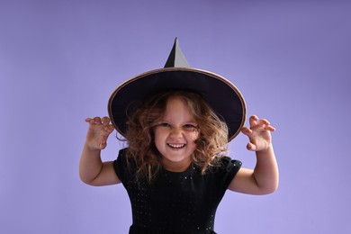 Photo of Funny girl dressed like witch for Halloween celebration on violet background