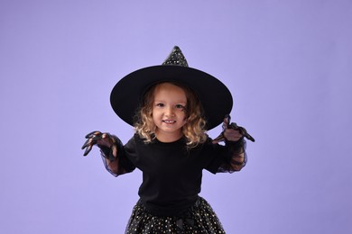 Funny girl dressed like witch on violet background. Halloween celebration