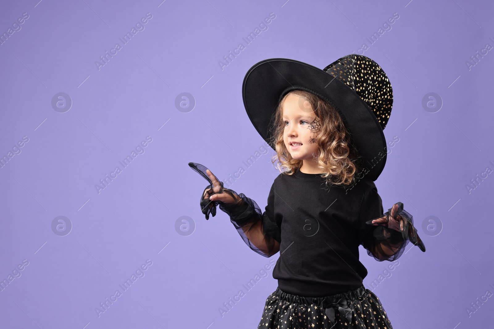 Photo of Funny girl dressed like witch for Halloween celebration on violet background, space for text