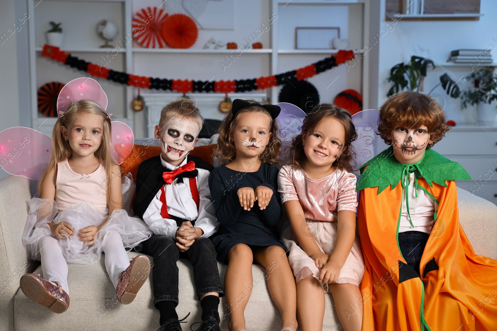 Photo of Funny children wearing costumes for Halloween celebration in room