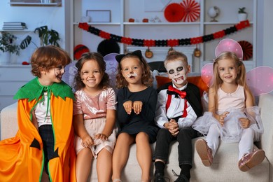 Funny children wearing costumes for Halloween celebration in room