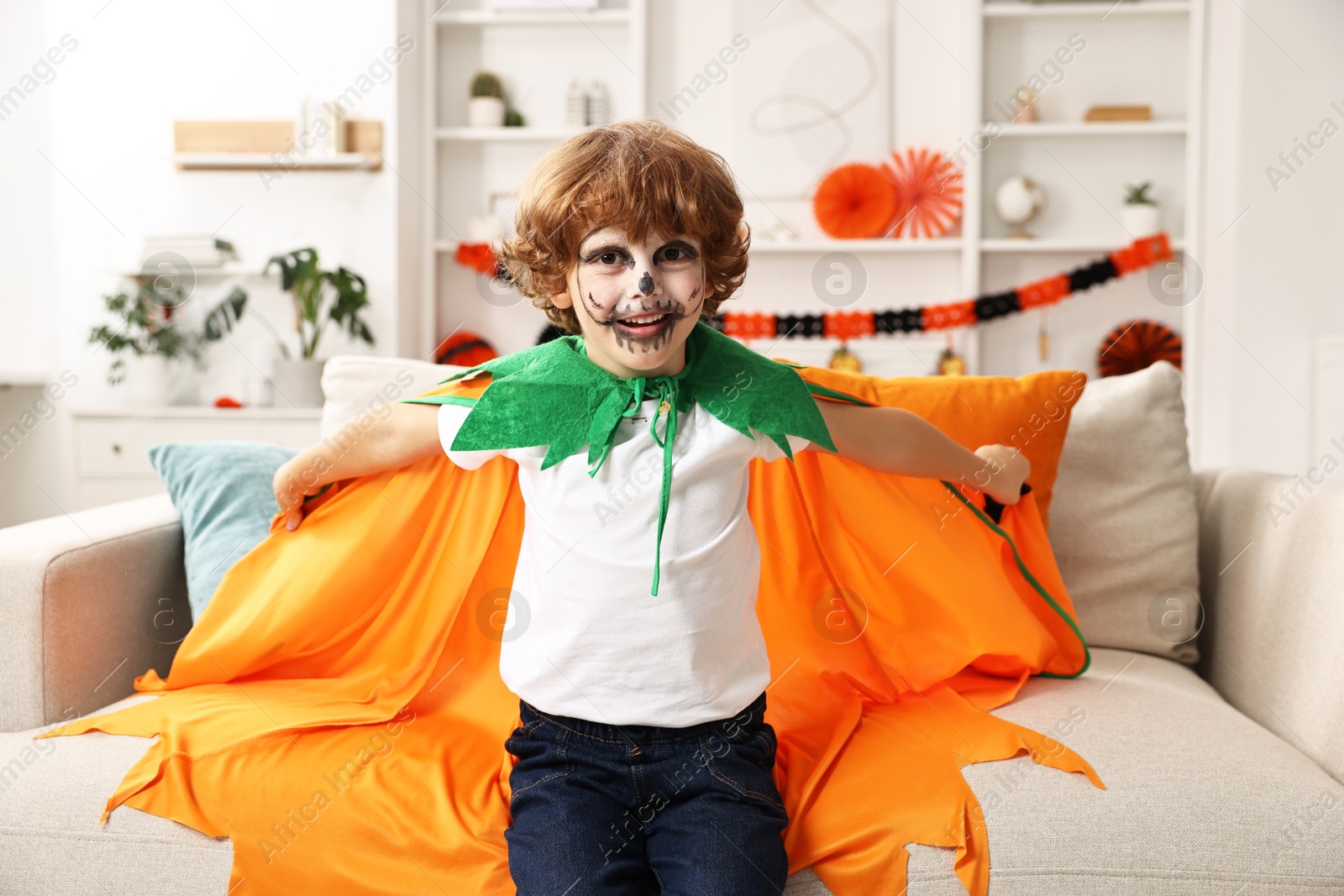 Photo of Funny boy dressed like pumpkin for Halloween celebration in room