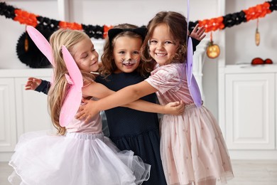 Photo of Cute girls wearing costumes for Halloween celebration in room