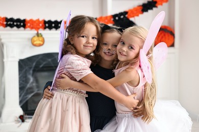 Photo of Cute girls wearing costumes for Halloween celebration in room