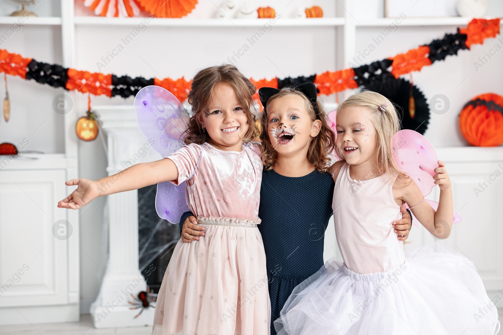 Photo of Cute girls wearing costumes for Halloween celebration in room