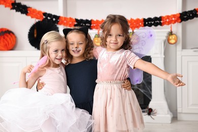 Photo of Cute girls wearing costumes for Halloween celebration in room