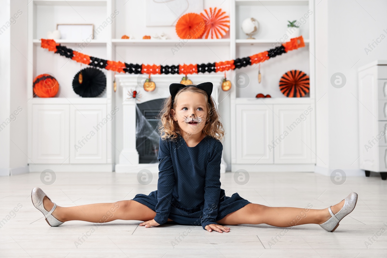 Photo of Cute girl dressed like cat for Halloween celebration in room