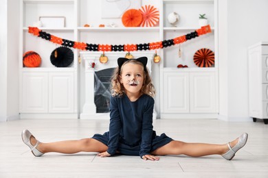 Cute girl dressed like cat for Halloween celebration in room