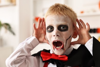 Photo of Funny boy dressed like vampire for Halloween celebration indoors