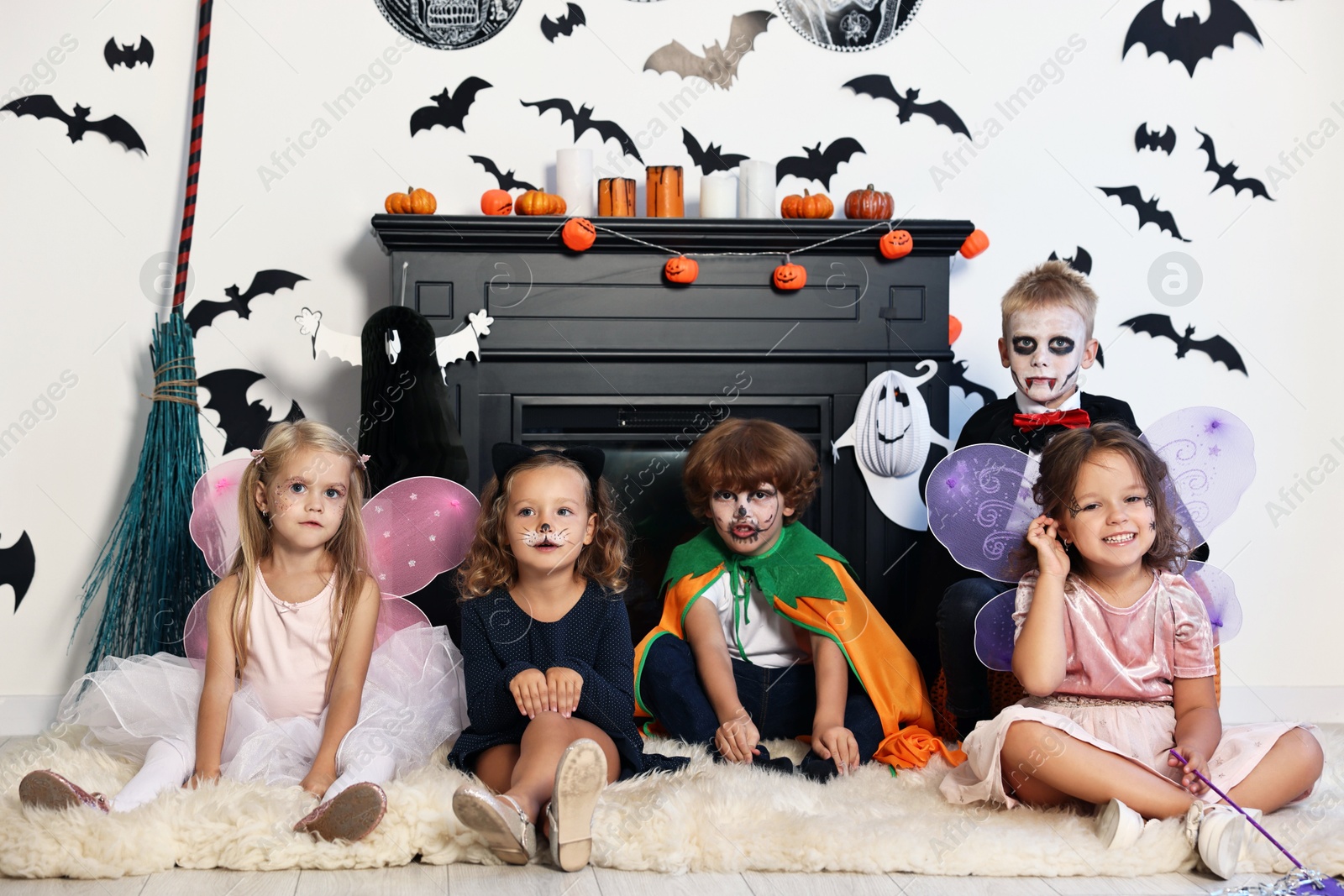 Photo of Funny children in costumes for Halloween celebration in decorated room