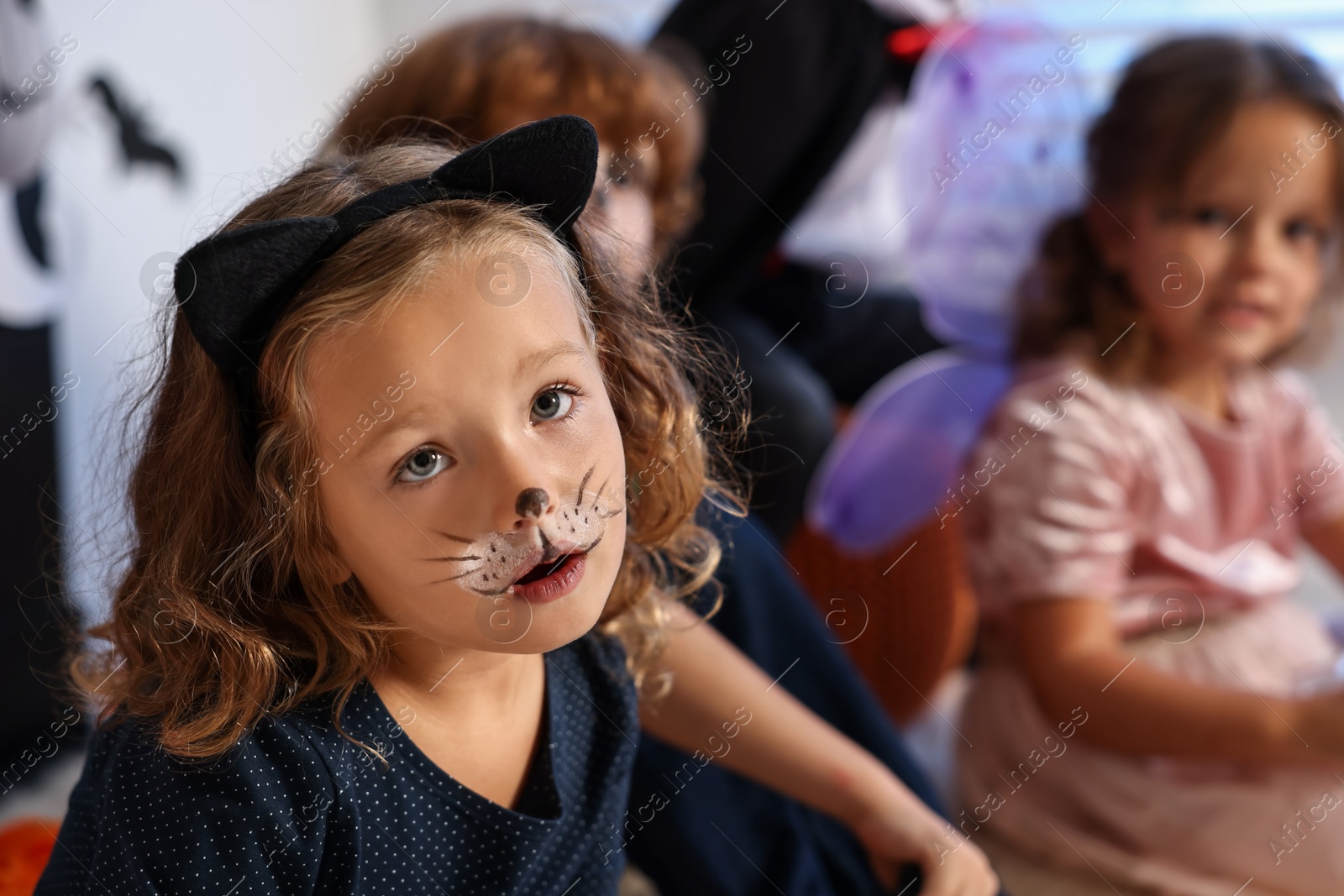 Photo of Funny children wearing costumes for Halloween celebration indoors, selective focus