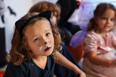 Photo of Funny children wearing costumes for Halloween celebration indoors, selective focus