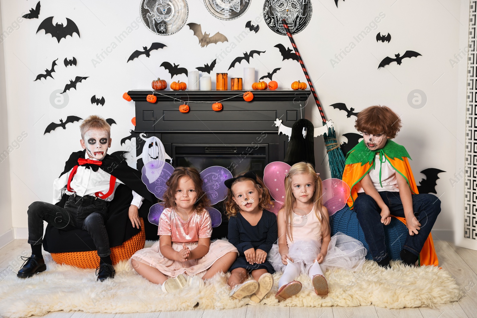 Photo of Funny children wearing costumes for Halloween celebration in decorated room