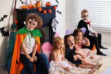 Funny children wearing costumes for Halloween celebration in room, selective focus