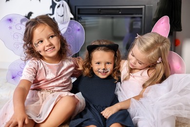 Photo of Cute girls wearing costumes for Halloween celebration in room