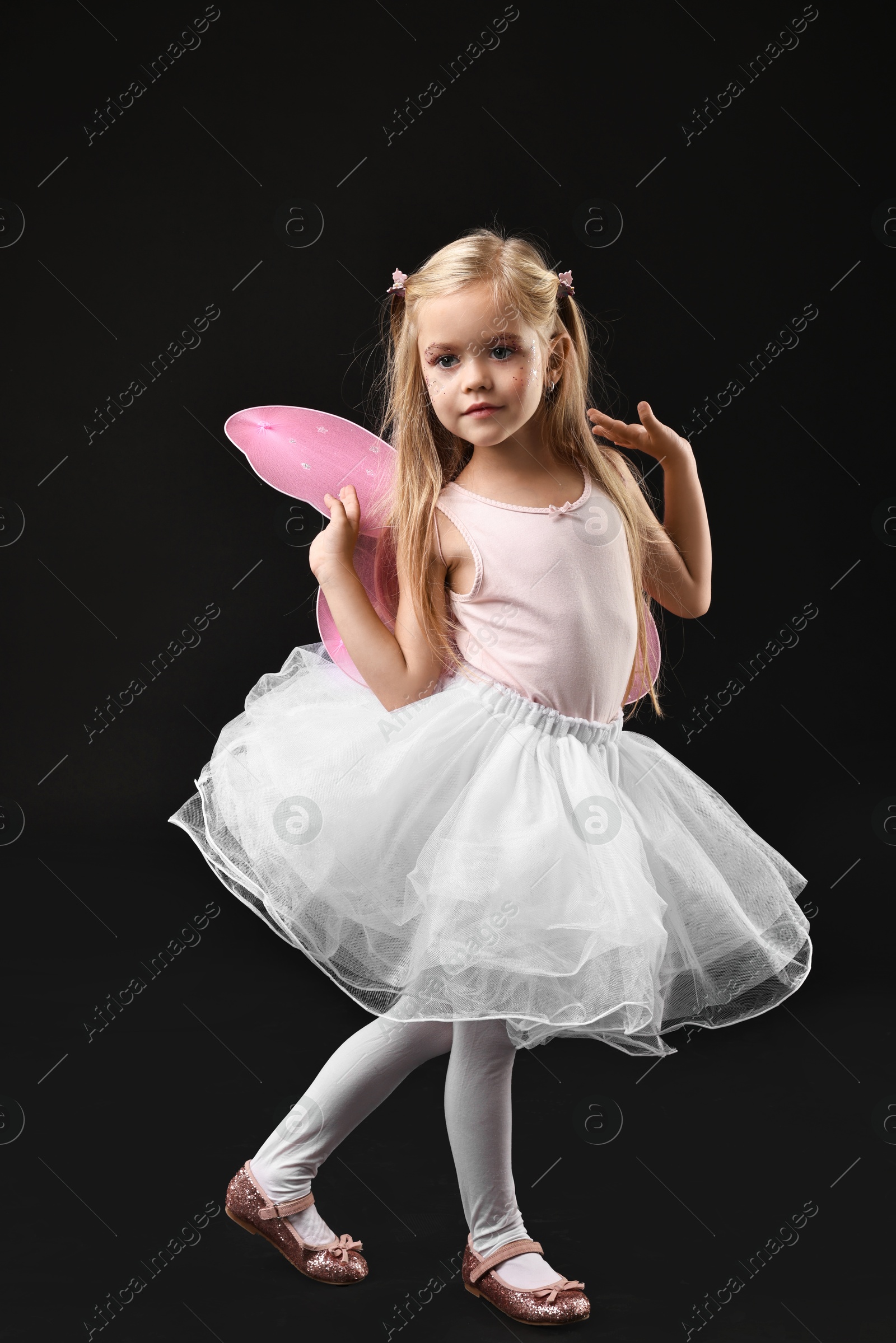 Photo of Cute girl dressed like fairy on black background. Halloween costume