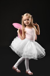 Cute girl dressed like fairy on black background. Halloween costume