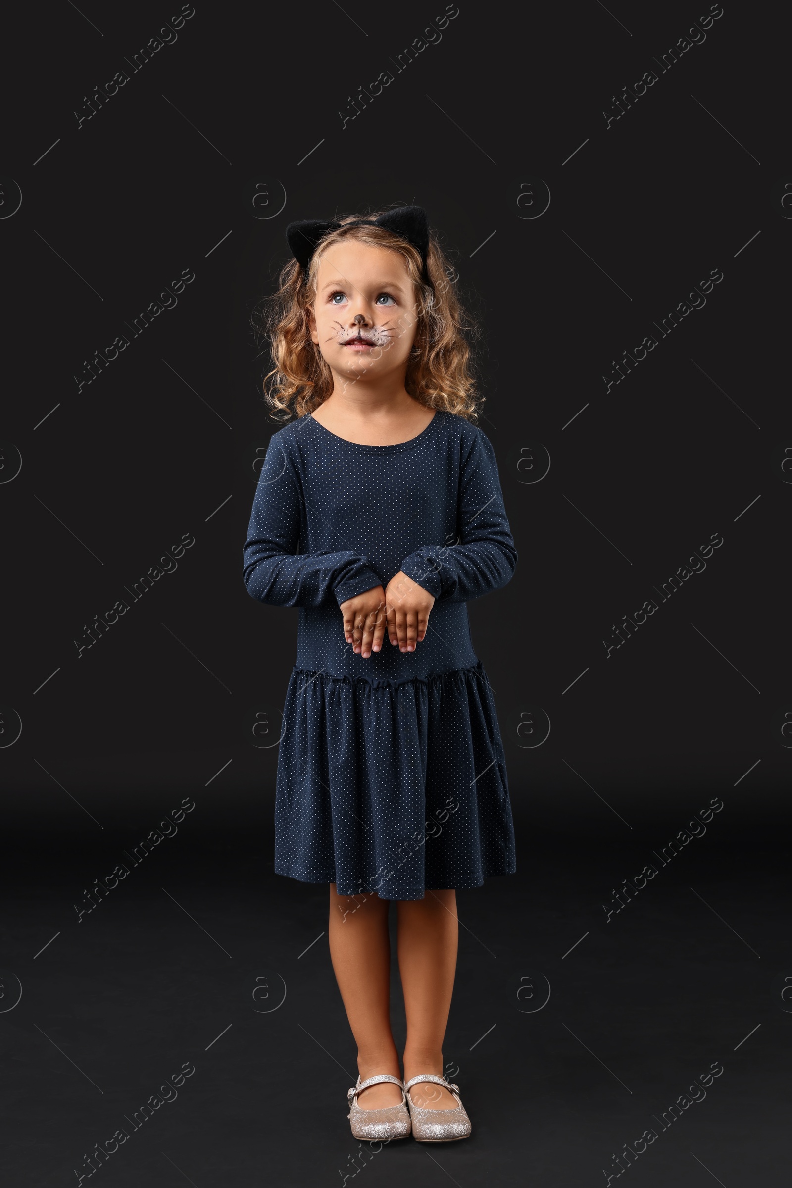 Photo of Funny girl dressed like cat for Halloween celebration on black background