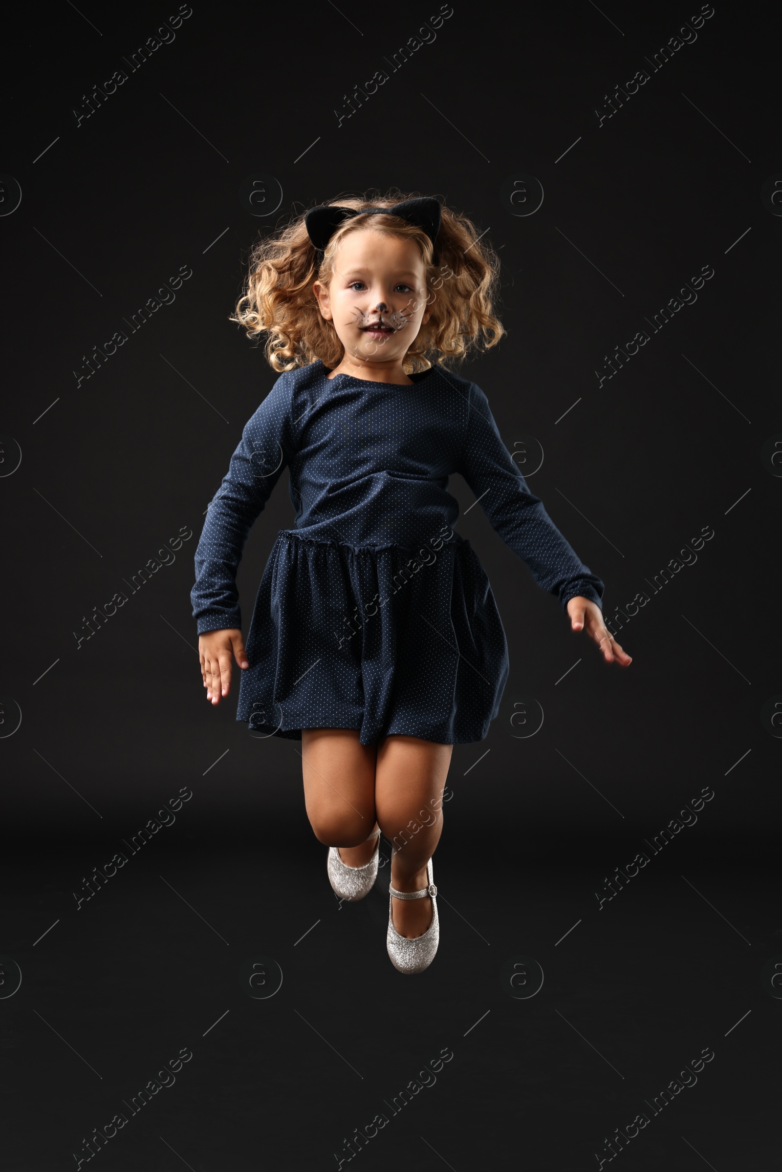 Photo of Funny girl dressed like cat for Halloween celebration on black background