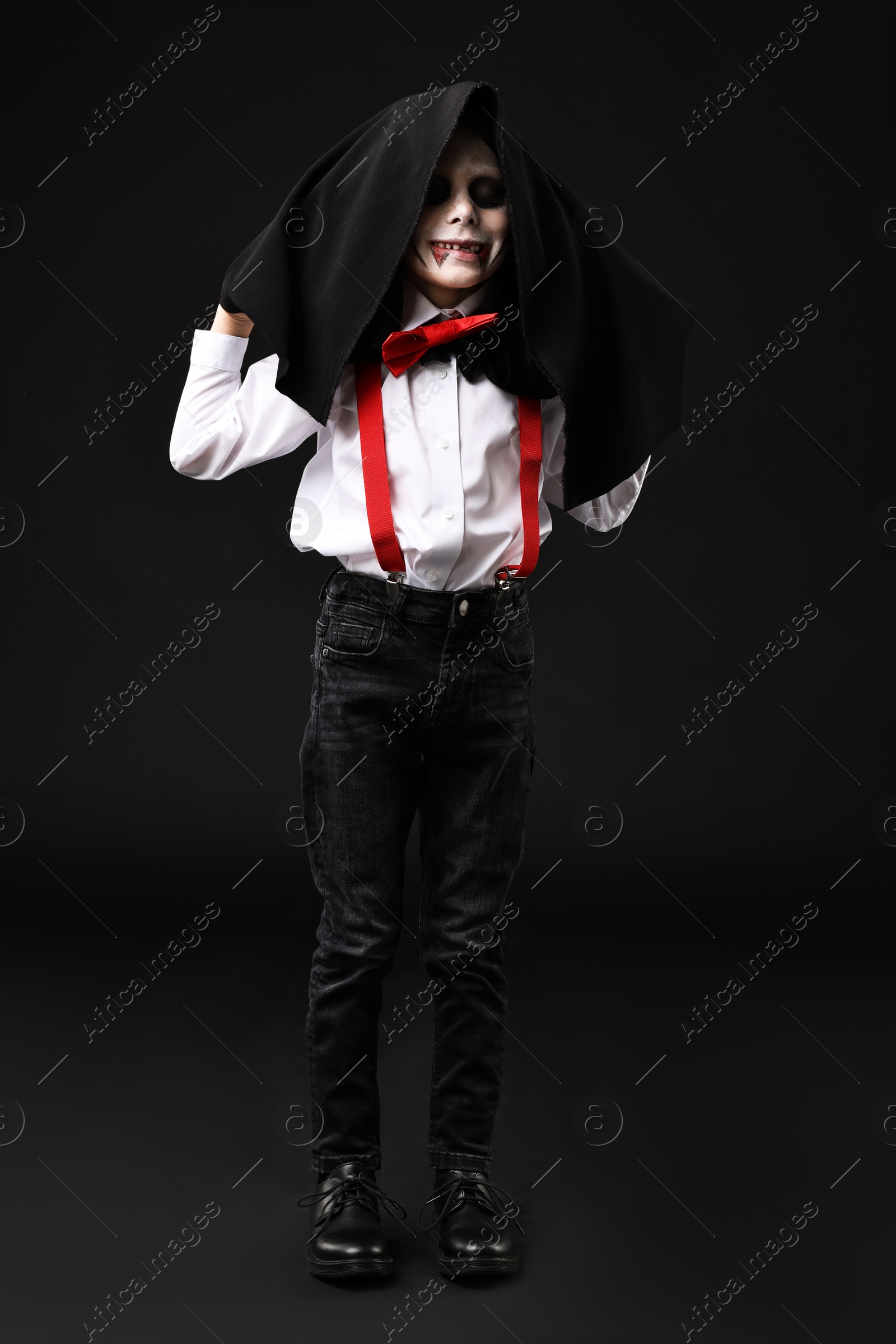 Photo of Funny boy dressed like vampire for Halloween celebration on black background