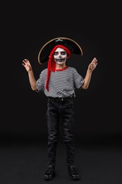 Photo of Funny boy dressed like pirate for Halloween celebration on black background