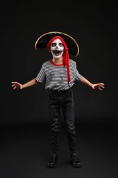 Photo of Funny boy dressed like pirate for Halloween celebration on black background