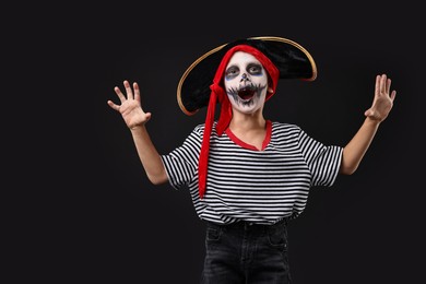 Funny boy dressed like pirate for Halloween celebration on black background