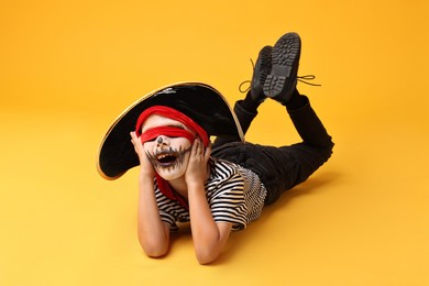 Photo of Funny boy dressed like pirate on yellow background. Halloween costume