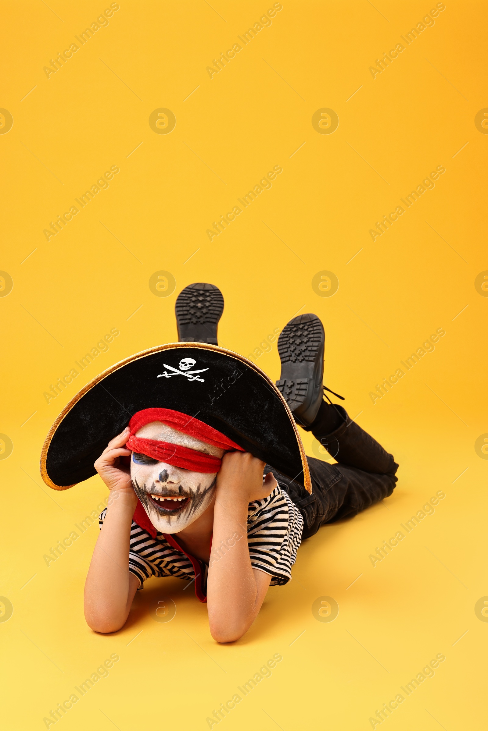 Photo of Funny boy dressed like pirate on yellow background. Halloween costume