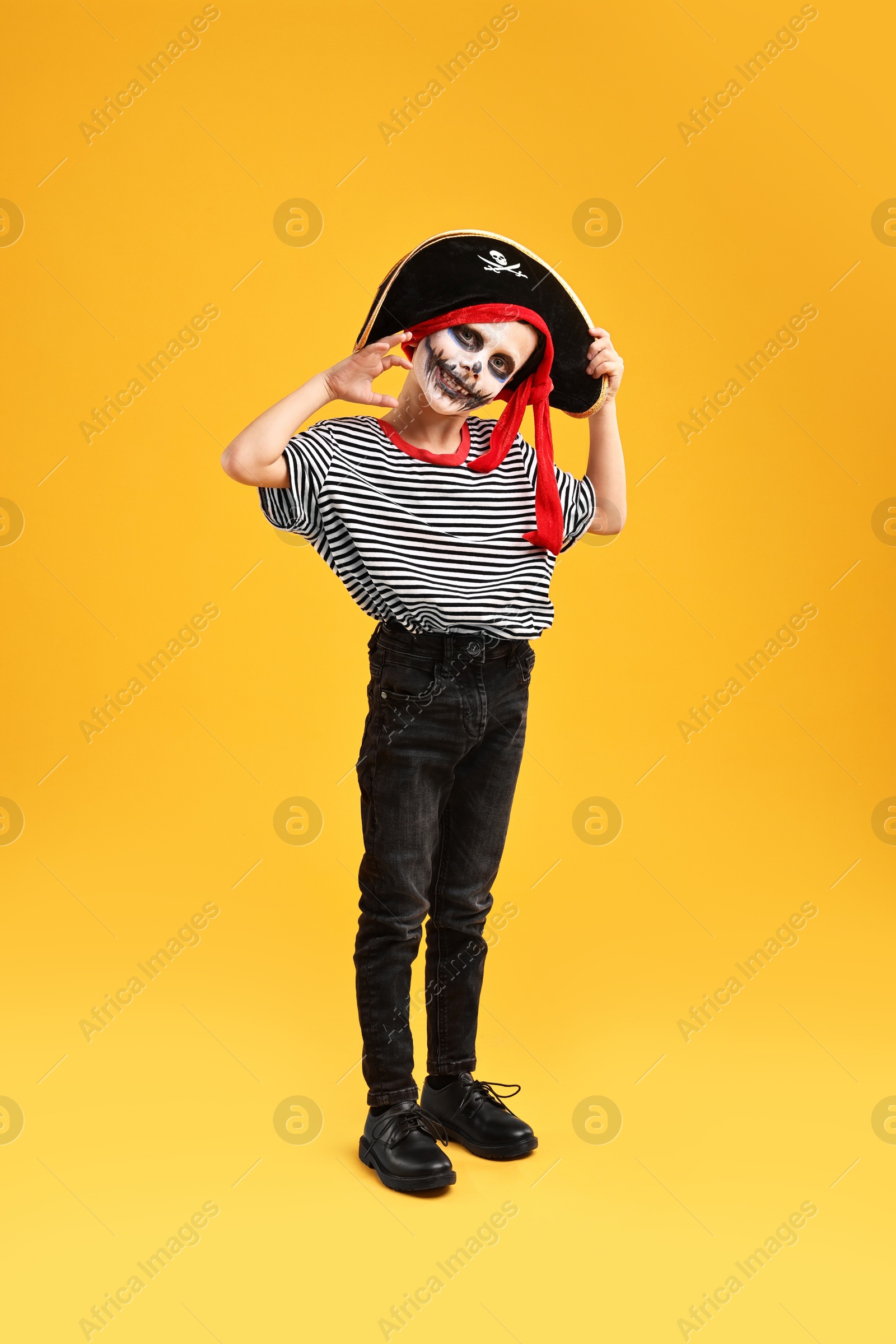 Photo of Funny boy dressed like pirate on yellow background. Halloween costume