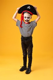 Photo of Funny boy dressed like pirate on yellow background. Halloween costume