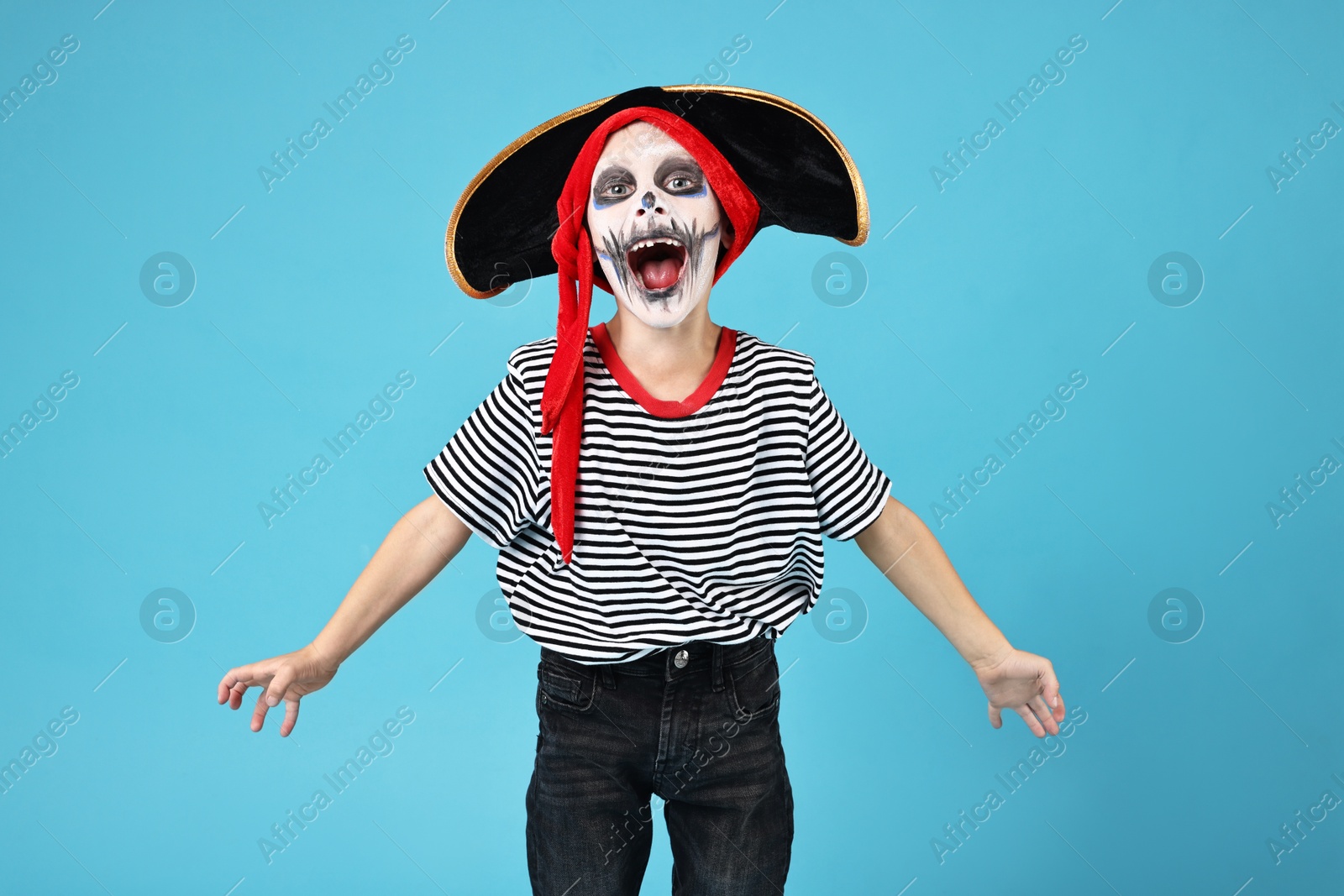 Photo of Funny boy dressed like pirate on light blue background. Halloween costume