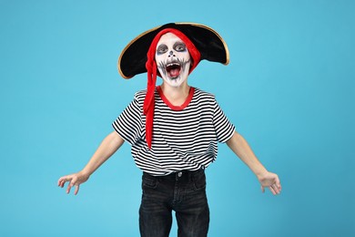 Photo of Funny boy dressed like pirate on light blue background. Halloween costume