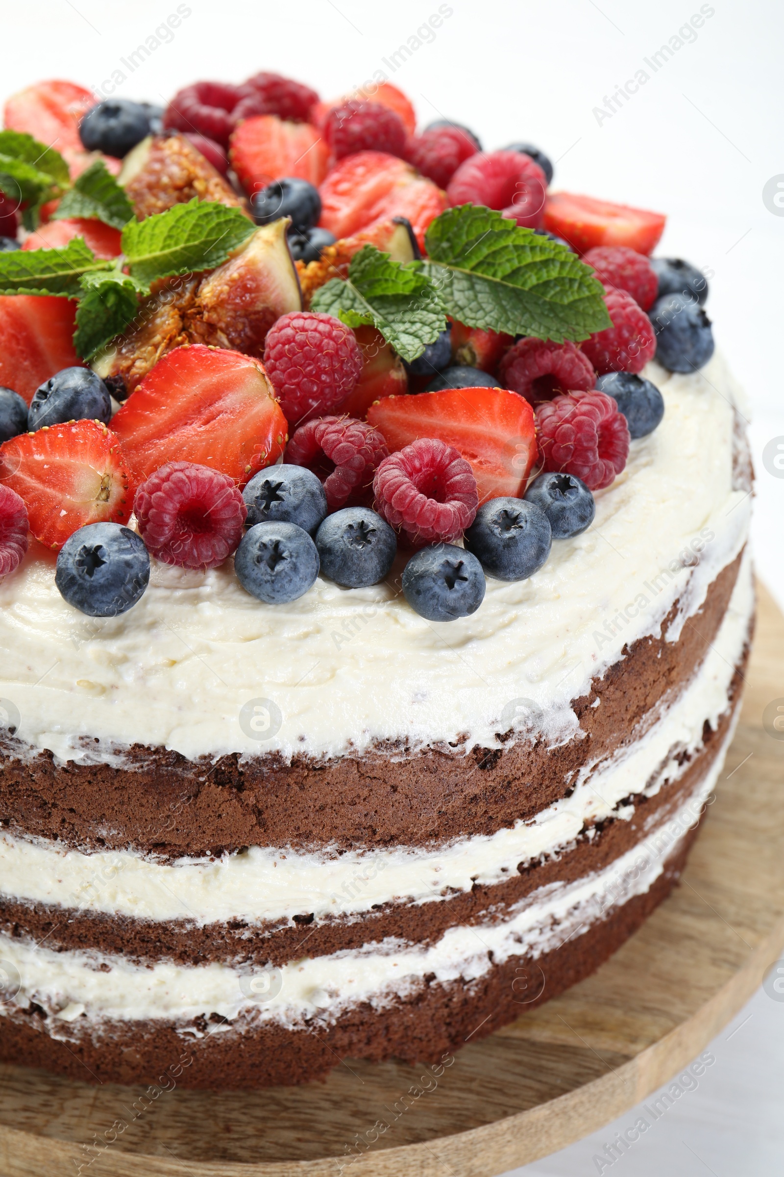 Photo of Delicious chocolate sponge cake with berries on light table, closeup