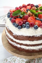 Delicious chocolate sponge cake with berries on light table, closeup