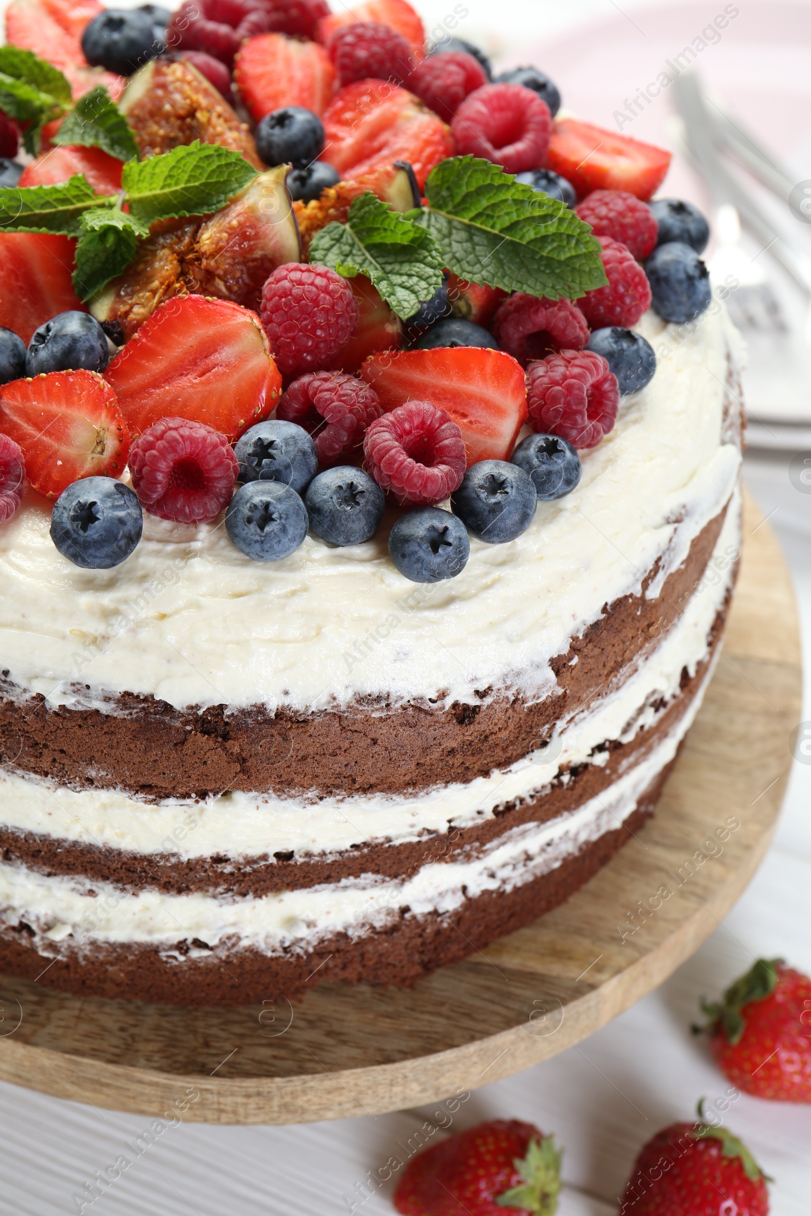 Photo of Delicious chocolate sponge cake with berries on light table, closeup