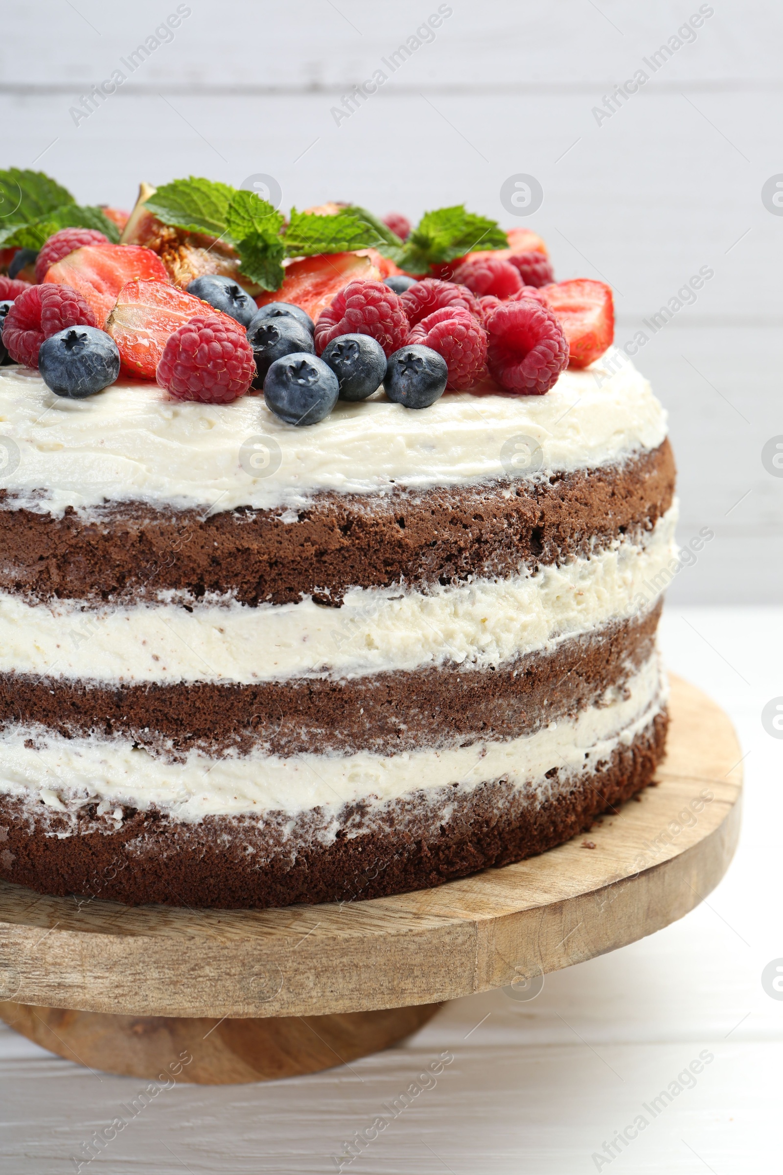 Photo of Delicious chocolate sponge cake with berries on light table, closeup