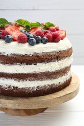 Delicious chocolate sponge cake with berries on light table, closeup